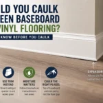 Baseboard and vinyl flooring showing the expansion gap and where caulk should be used