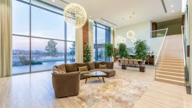 Modern living room with glass railings on stairs, large windows, and stylish interior design for enhanced safety and elegance.