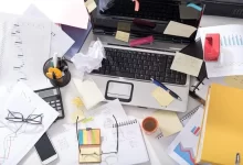 Messy office desk cluttered with papers, sticky notes, and office supplies, impacting productivity and organization.