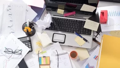 Messy office desk cluttered with papers, sticky notes, and office supplies, impacting productivity and organization.