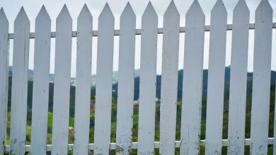 A white vinyl fence gate offering low maintenance and durability with a scenic view in the background.