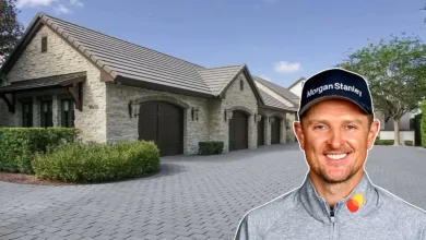 Justin Rose smiling in front of luxury stone house with circular driveway and landscaped grounds