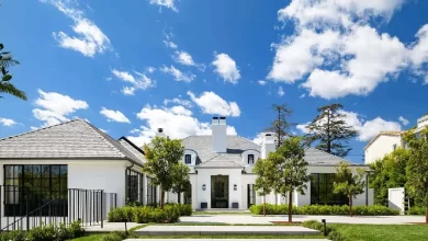 Beautiful white Brentwood House exterior featuring Spanish Colonial architecture with manicured landscaping and blue sky