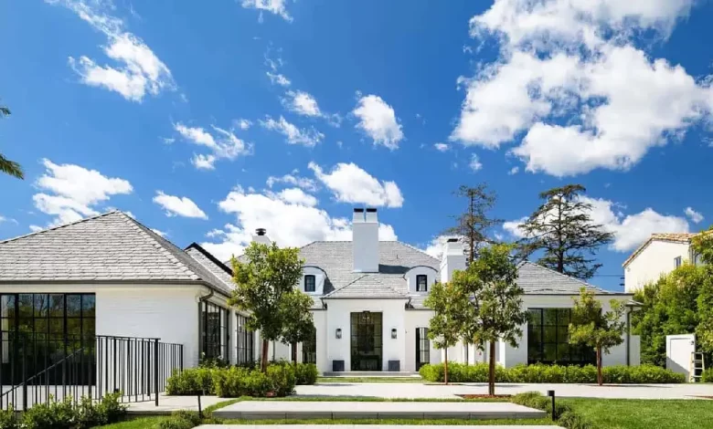 Beautiful white Brentwood House exterior featuring Spanish Colonial architecture with manicured landscaping and blue sky