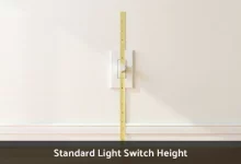 Standard light switch height measured at 48 inches from floor with tape measure on residential wall