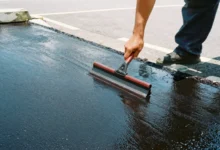 Professional applying pavement maintenance sealcoat treatment to protect parking lot surface from weather damage and cracks