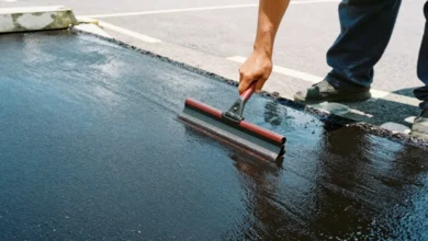 Professional applying pavement maintenance sealcoat treatment to protect parking lot surface from weather damage and cracks