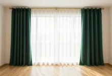 Floor-length green curtains in a bright living room with white walls and brass curtain rod