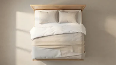 A neatly made bed with a white inexpensive mattress and neutral bedding in a simple bedroom setting
