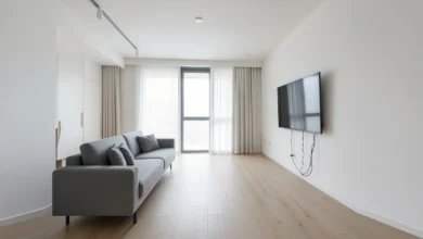 A minimalist living room showcasing smart home interior design with recessed lighting, motorized shades, and a flush-mounted smart control panel