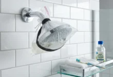 Person cleaning a shower head with a plastic bag filled with white vinegar to remove limescale and mineral deposits