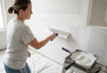 Person using a taping knife to skim coat a wall with white joint compound