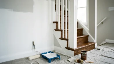 Paint walls before staining stairs — paint roller on white wall next to wood stained staircase